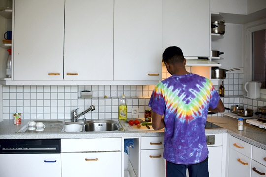 Mann steht in der Küche und bereitet sich eine Mahlzeit zu