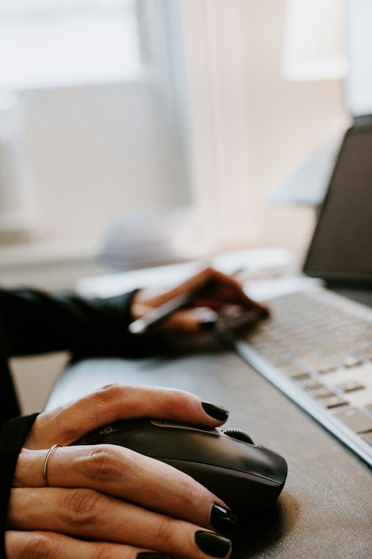 Person sitzt vor dem Computer und bedient die Maus